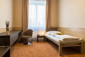 a bedroom with a bed and a chair and a window at Hotel Lužnice in Planá nad Lužnicí