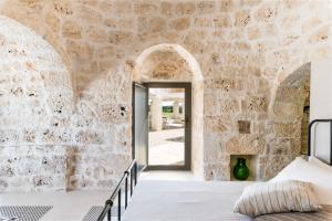 a bedroom with a stone wall and a doorway at Trullo La Dolina con piscina e dependance by Wonderful Italy in Ostuni +34 photos