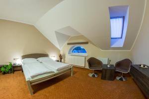 a bedroom with a bed and two chairs and a window at Hotel Lužnice in Planá nad Lužnicí