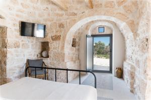 a bedroom with a bed in a stone wall at Trullo La Dolina con piscina e dependance by Wonderful Italy in Ostuni