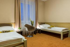 a hotel room with two beds and a chair at Hotel Lužnice in Planá nad Lužnicí