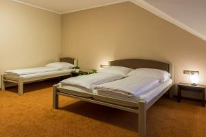 a bedroom with two beds with white sheets and lamps at Hotel Lužnice in Planá nad Lužnicí