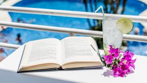 an open book on a table with a drink and flowers at Apartamentos El Faro By Mc in Benidorm +24 photos