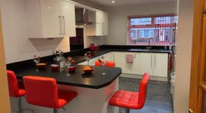 a kitchen with a black counter and red chairs at Wallace View - Holiday Home in Stirling