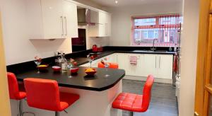 a kitchen with a black counter and red chairs at Wallace View - Holiday Home in Stirling