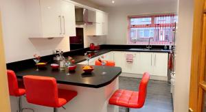 een keuken met een zwart aanrecht en rode stoelen bij Wallace View - Holiday Home in Stirling