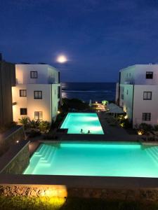 a large swimming pool in front of two buildings at night at East Coast Beachfront Luxury - Eastern Blue Apartments in Poste Lafayette