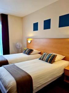 2 camas en una habitación de hotel con cuadros azules en la pared en Hotel Restaurant 't Trefpunt, en Made