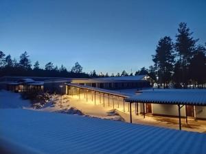 a large building with snow on the ground and lights at Hotelli Hiittenharju in Harjavalta