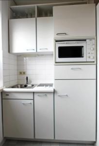 eine weiße Küche mit weißen Schränken und einer Mikrowelle in der Unterkunft Moin Moin in Hörnum