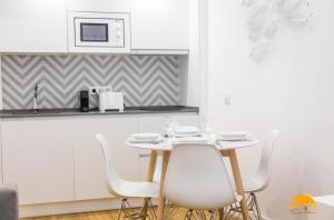 uma cozinha branca com uma mesa e cadeiras brancas em Estudio Gaviota by Cadiz Time em Cádiz