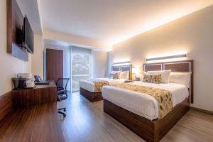 グアダラハラにあるSleep Inn Guadalajara Galeriasのベッド2台とテレビが備わるホテルルームです。