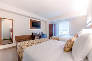 a hotel room with two beds and a mirror at Sleep Inn Guadalajara Galerias in Guadalajara