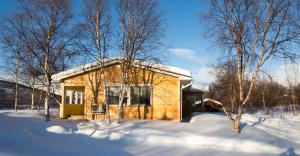 una pequeña casa en la nieve con árboles nevados en Villa Kinos, en Utsjoki