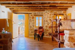 una sala de estar con suelo de madera y paredes de piedra. en Stenosa, en Donoussa