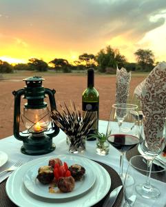 a table with a plate of food and a bottle of wine at Gamagara Africa Private Nature Reserve in Kathu