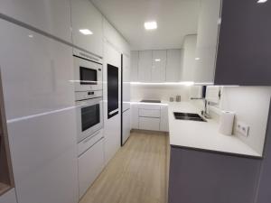 una cocina blanca con encimeras y electrodomésticos blancos en Casa Viento de Levante, en Cádiz