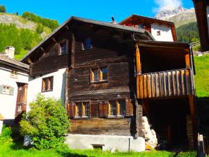 une vieille maison en bois avec un garage en face de celle-ci dans l'établissement Haus Nicca, à Splügen