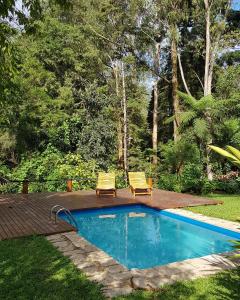 a swimming pool with two chairs and a deck at Chalés Mathora in Visconde De Maua