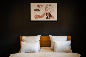 łóżko z białymi poduszkami i zdjęciem nad nim w obiekcie Cabana Haiducului Doftana w mieście Teşila