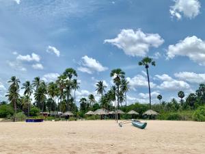 a beach with palm trees and a blue boat on it at 108 Palms Beach Resort in Trincomalee