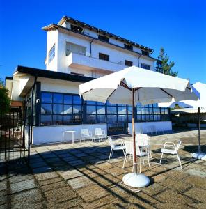 a white umbrella and chairs in front of a building at B&B Loreblick in Loreto Aprutino