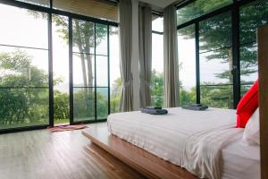 una camera da letto con ampie finestre e un letto bianco di Baan Phu Pa Pha บ้านภูปภา a Nakhon Ratchasima