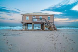 a house on the beach with footprints in the sand at Midsummer Solstice in Dauphin Island