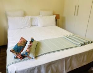 a large white bed with two pillows on it at Garden and Park Leisure on Tugela in Benoni