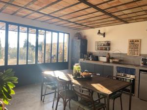 a kitchen with a wooden table and chairs and windows at MAS DES 2 PLATANES in Arles