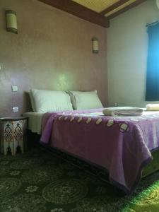 a bedroom with two large beds with purple sheets at Dar Diafa Kaltom in Ouzoud