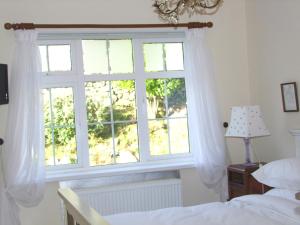 Schlafzimmer mit einem Fenster mit weißen Vorhängen und einem Bett in der Unterkunft Glendalough 11 Minutes from Beautiful Farmhouse Apartment in Wicklow