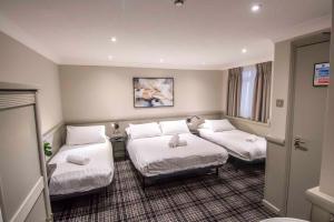una camera d'albergo con due letti con lenzuola bianche di Howard Winchester Hotel a Londra