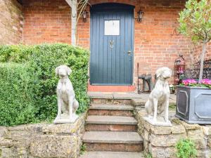 Deux statues de chiens devant une maison dans l'établissement The Cheese Room, à Moreton-in-Marsh