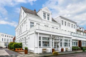 ein weißes Gebäude mit Balkon auf einer Straße in der Unterkunft Hotel Aquamarin in Norderney