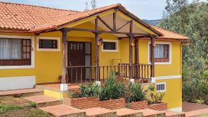 Casa amarilla con porche y balcón en Quinta Los Llanitos Hospedaje Campestre, en Guatavita