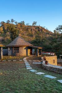 a small stone building with a hill in the background at Turban Nature Wilderness Resort, Kumbhalgarh in Kumbhalgarh