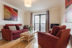 a living room with two red chairs and a table at PREMIER SUITES Bristol Redcliffe in Bristol