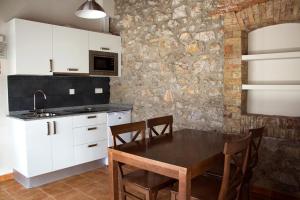a kitchen with white cabinets and a table with chairs at Hotel y Apartamentos El Camín in Llanes