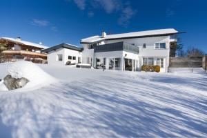 a white house with a pile of snow in front of it at Villa Mama - Luxus und Lebensfreude in Seefeld in Tirol