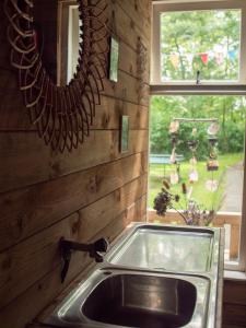 ein Waschbecken in einer Küche mit einem Spiegel und einem Fenster in der Unterkunft Buitenplaats de Oorsprong in Brouwershaven