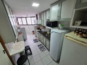 a kitchen with white cabinets and a white refrigerator at APT Encantador Centro Guarapari, completo, 50 m da praia in Guarapari