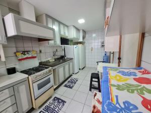 a kitchen with white cabinets and a stove top oven at APT Encantador Centro Guarapari, completo, 50 m da praia in Guarapari