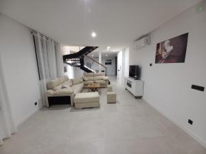 una sala de estar con muebles blancos y una escalera. en Las Pasaeras en Montehermoso