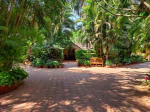 una pasarela con palmeras y un banco en un parque en Palm Grove Cottages - Leisure Resort en Benaulim