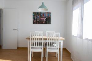 La Pedriza One في مانزاناريس إل ريال: طاولة طعام مع كراسي بيضاء و لوحة على الحائط