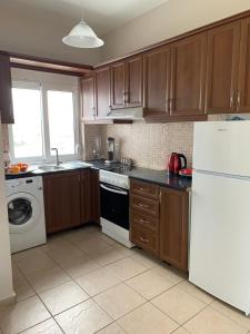 eine Küche mit Holzschränken und einem weißen Kühlschrank in der Unterkunft Almyrida milly's apartment I in Chania