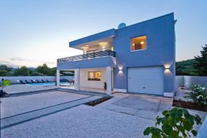 a large blue house with a garage at FAMILY VILLA WITH POOL-Peaceful Hvar Island Oasis in Bogomolje