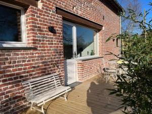 a bench sitting on a deck next to a brick building at La muche 2 in Marquillies