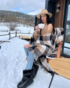 a woman sitting in the snow holding a cup of coffee at Blog House Resort in Yaremche